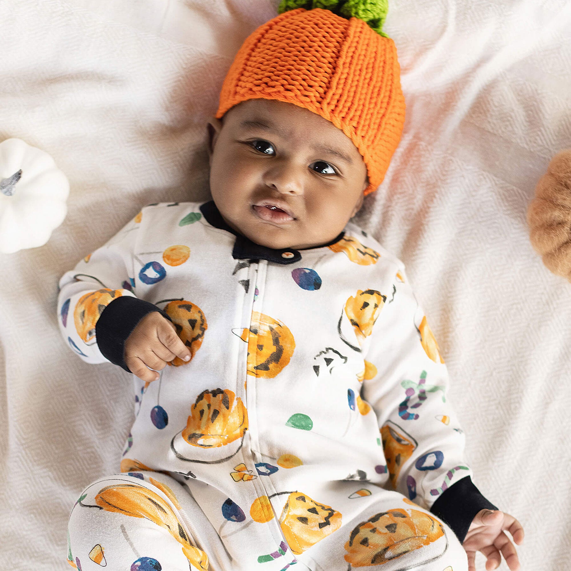 Baby boy wearing Burt's Bees Baby organic cotton Halloween pajamas and pumpkin hat